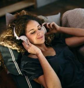 a woman laying on a couch with her eyes closed and wearing headphones