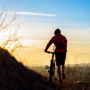 A person in a red jacket riding a bicycle on a trail.