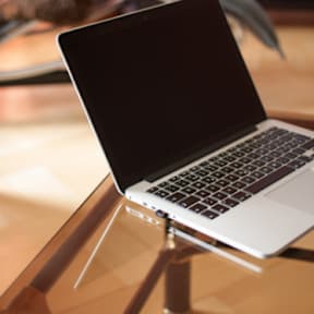 A MacBook Pro is placed on a wooden stand.