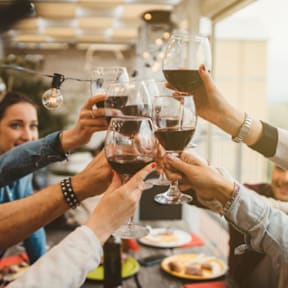 A group of people toasting with glasses of red wine.