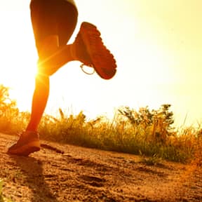 A person is running on a dirt path during sunset.