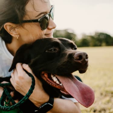 Woman Smiling while Holding Dog