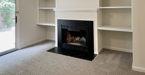 a living room with a fireplace and built in shelving