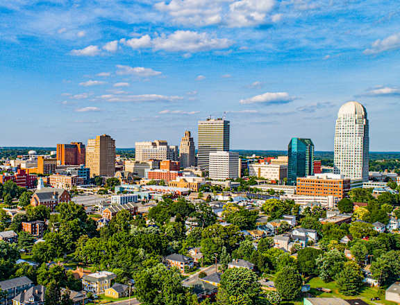 A cityscape with a mix of modern and older buildings, surrounded by greenery.