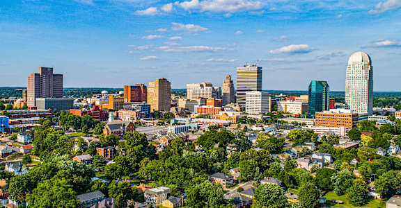 A cityscape with a mix of modern and older buildings, surrounded by greenery.