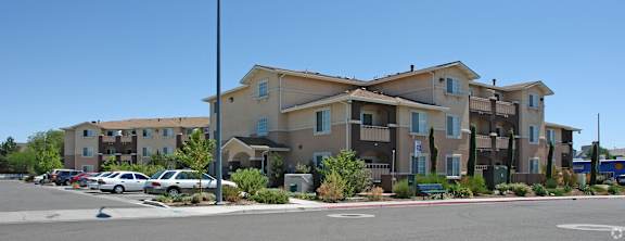 Apartment complex with a parking lot in front.