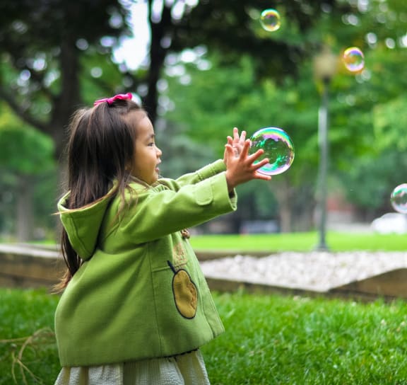 a young girl playing with soap bubbles in a park