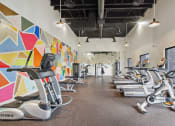 Thumbnail 11 of 13 - a gym with treadmills and weights and a colorful wall