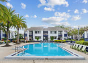 Thumbnail 8 of 13 - a swimming pool in front of a building with palm trees