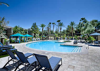 A pool surrounded by palm trees and lounge chairs.
