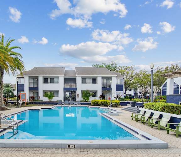 a swimming pool in front of a building with a resort style pool