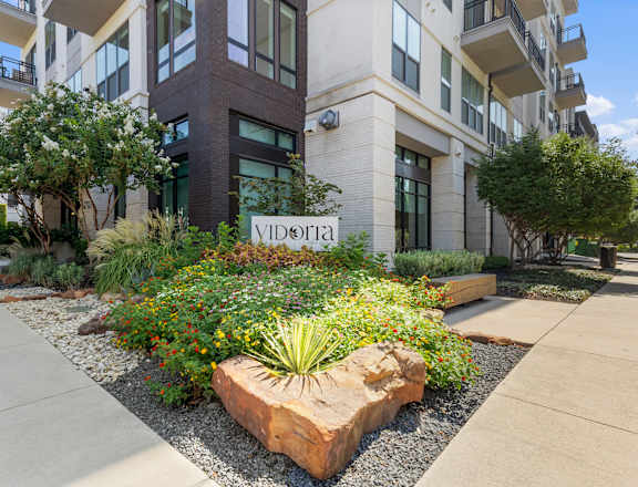 A garden in front of a building with the name "Victoria" on it.