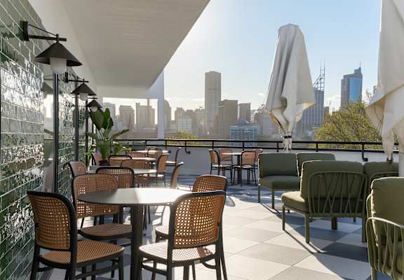 A patio with tables and chairs overlooking a city skyline.
