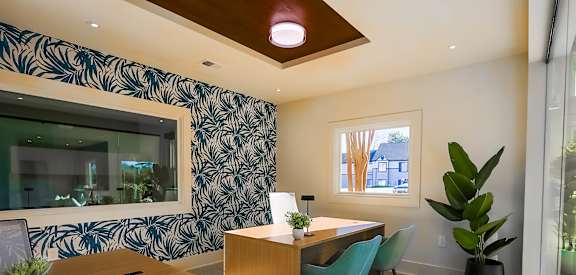 A room with a desk and chairs with a green chair in front.