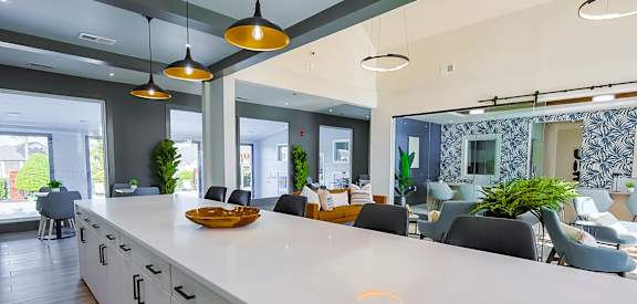 A modern kitchen with a long white counter and grey cabinets.