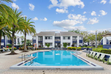 a swimming pool in front of a building with palm trees