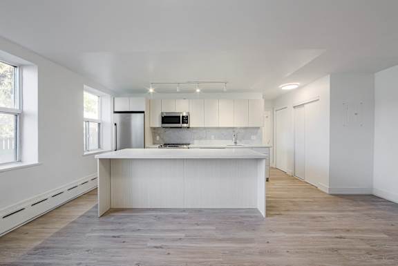 A kitchen with white cabinets and a white island with a sink.at 111 Cosburn, Ontario