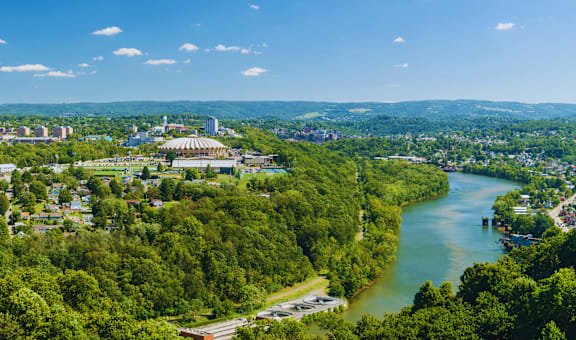 A river flows through a green valley with a city in the background.