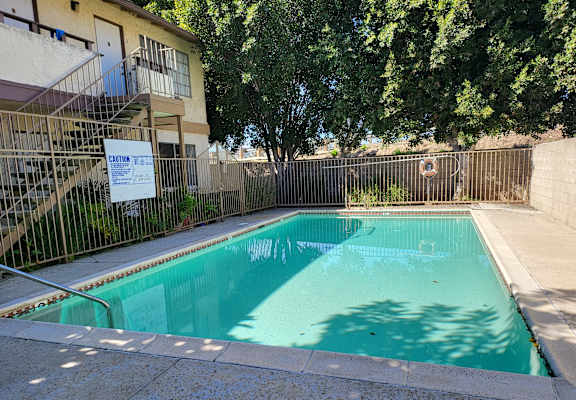 a swimming pool in front of a building with a fence