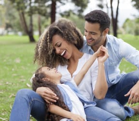 a man and woman sitting on the grass with a child