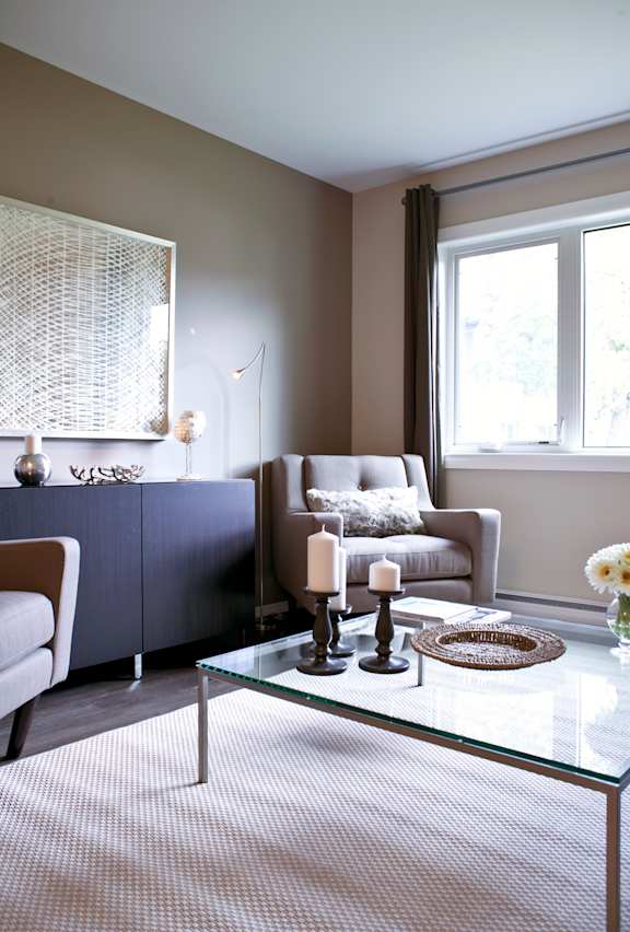 A modern living room with a glass coffee table and a grey sofa.