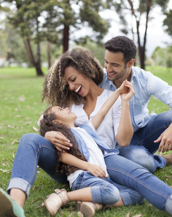 a man and woman sitting on the grass with a child