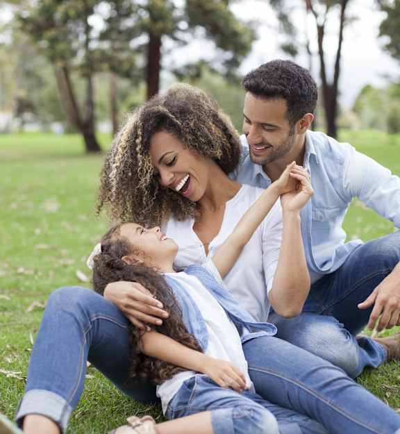 a man and woman sitting on the grass with a child