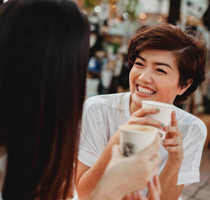 girl smiling at friend holding cup