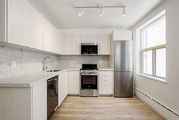A kitchen with white cabinets and a marble countertop.at 111 Cosburn, East York