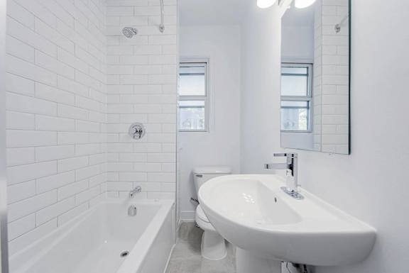 A white bathroom with a tub, toilet, and sink.at 83-85 Silver Birch, Toronto