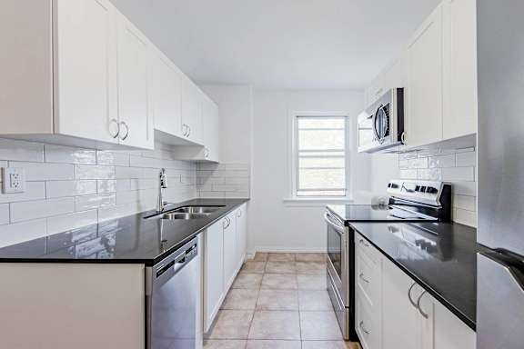 A kitchen with white cabinets and black countertops.at 83-85 Silver Birch, Toronto