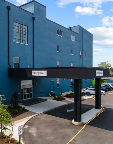 a blue building with a black awning in front of a parking lot