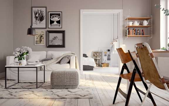 A living room with a white sofa, a grey ottoman, a wooden chair and a white door.
