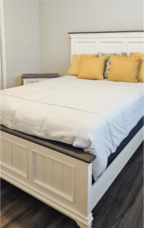 a white bed with a white headboard and pillows on it