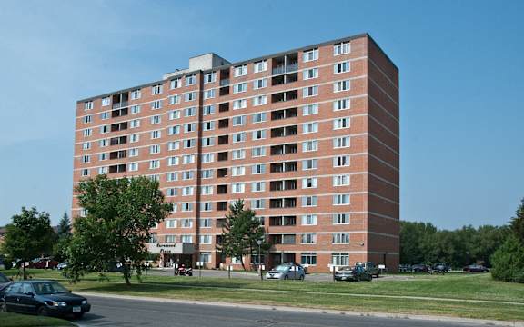 A large red brick apartment building with a parking lot in front.