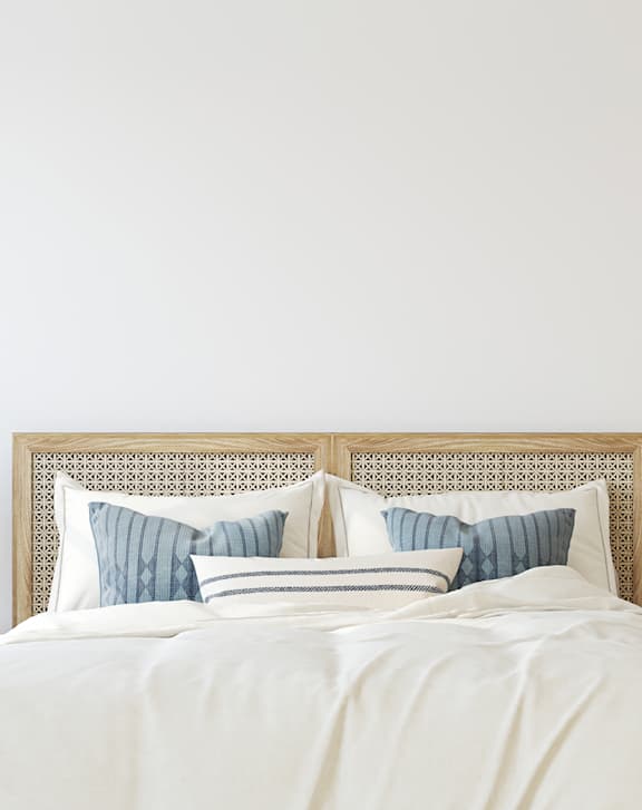 A bed with a white comforter and a headboard with a pattern on it.