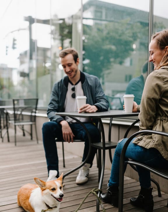 a dog sitting on a leash in front of people sitting at a table