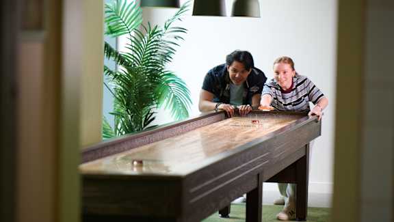 Two people playing a game on a long table.