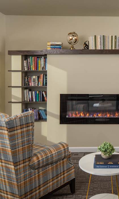 A living room with two plaid chairs, a coffee table, and a fireplace.