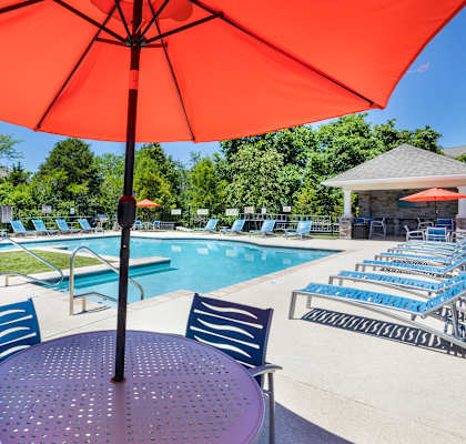 our apartments have a pool and patio with chairs and an umbrella
