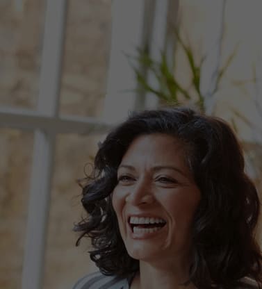 A woman with dark hair is smiling at a nice restaurant.