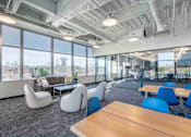 Thumbnail 17 of 24 - A modern office space with blue chairs and wooden tables.