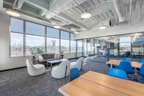 A modern office space with blue chairs and wooden tables.