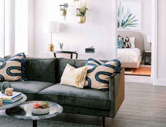 A living room with a grey couch and a glass table.