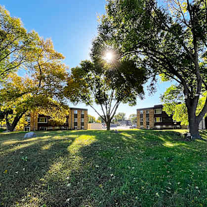 A sunny day in a park with a building in the background.