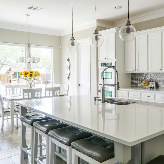 A kitchen with a white island and bar stools.