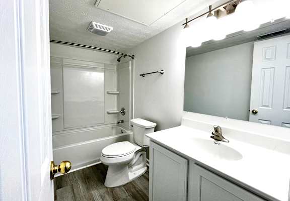 A white toilet sits in a bathroom next to a sink.