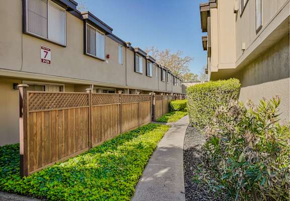 a long wooden fence separates the two buildings of an apartment complex