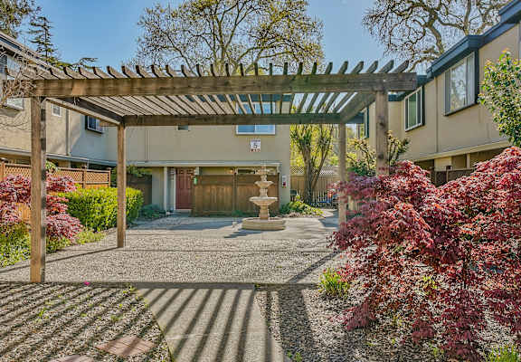 a pergola with a fountain in front of a building
