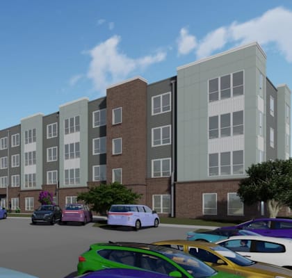 A parking lot with cars and a bus in front of apartment buildings.